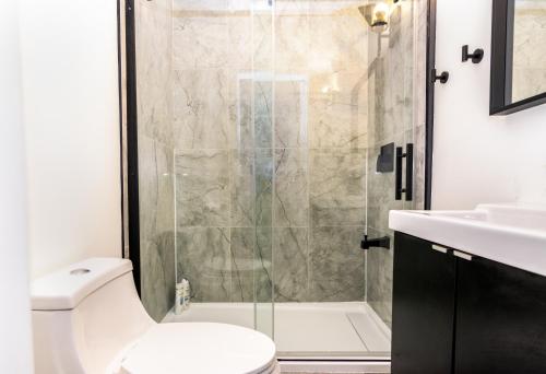 a bathroom with a shower and a toilet and a sink at Downtown Retreat-Spacious Rooms with Shared Kitchen & Bath in Toronto