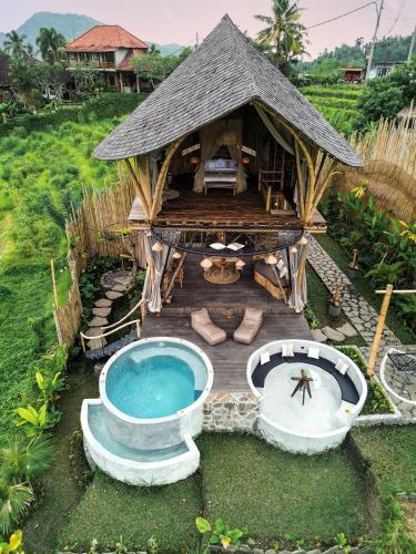 a hut with a swimming pool and a deck at Nivriti Bali in Sidemen