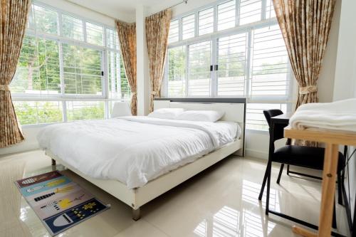 a bedroom with a bed and a desk and windows at อรุณวิภา บ้านพักสำหรับครอบครัว อำเภอเมืองหนองคาย in Ban Na Kai