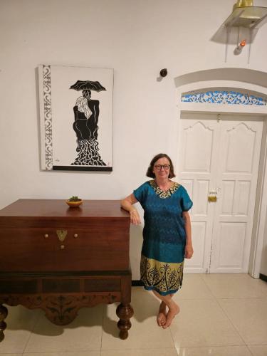 a woman standing next to a table in a room at Sudu Colonial House 1929 in Ambalangoda