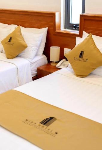 a hotel room with two beds with yellow pillows at Mira Eco Hotel Quy Nhon in Quy Nhon