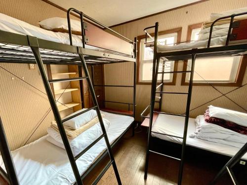 a room with two bunk beds in a dorm room at IZA Kamakura Guest House and Bar in Kamakura
