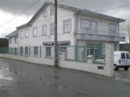 uma casa branca com um carro estacionado em frente dela em Hostal Catro Ventos em Lugo