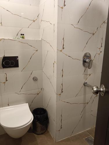 a bathroom with a toilet and a marble wall at Hotel Lohmod on Main Highway Opp of Aerocity in New Delhi