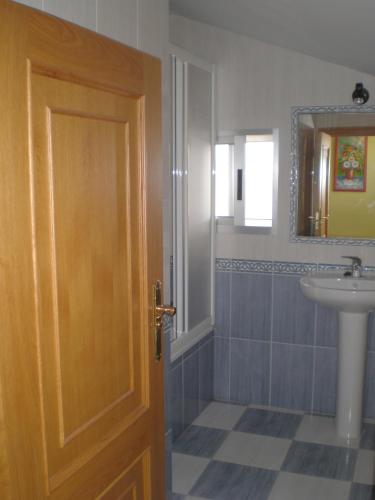 a bathroom with a wooden door and a sink at Hostal Catro Ventos in Lugo
