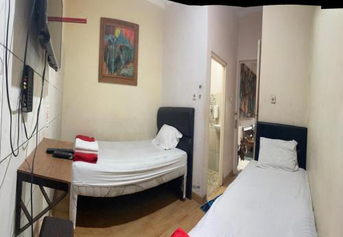 a room with two beds and a table and a desk at Art Guest House Syariah by Secoms in Timuran