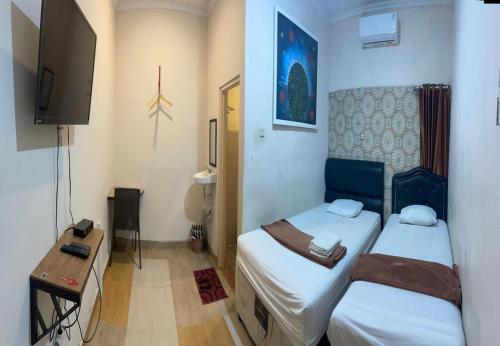 a small room with two beds and a television at Art Guest House Syariah by Secoms in Timuran