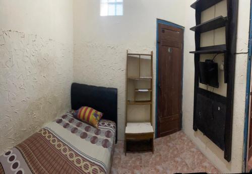 a small room with a bed and a cabinet at Art Guest House Syariah by Secoms in Timuran