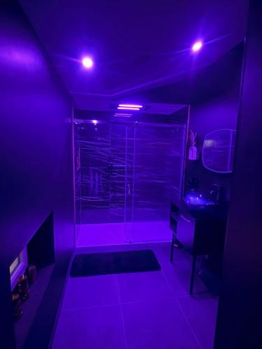 La salle de bains est pourvue d'une douche avec des lumières violettes. dans l'établissement Sweety's Eden Jacuzzi - Spa privé Sauna Cinéma room Jardin - Terrasse centre-ville, au Mans