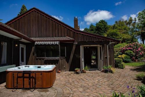 a hot tub sitting on a patio in front of a house at Mountain Bike Manor in Rotorua
