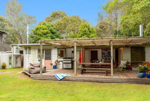 a house with a wooden deck with a grill at Merricks Surf Cottage - Charming Beachfront Bliss in Merricks