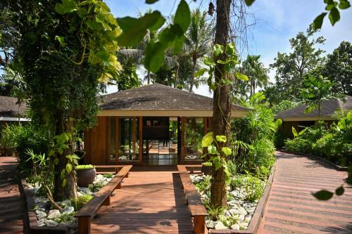 a house with a wooden walkway leading to the front yard at Barcelo Coconut Island, Phuket in Phuket Town