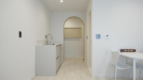 a white kitchen with a table and a sink at Stay Yongdam in Jeju