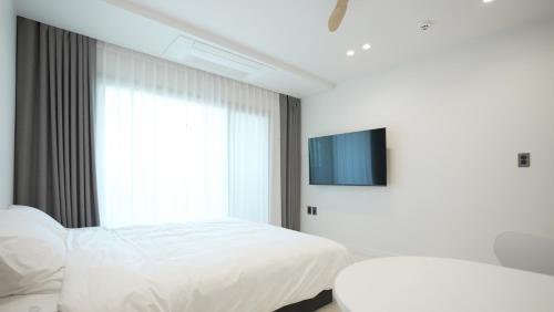 a bedroom with two white beds and a tv at Stay Yongdam in Jeju