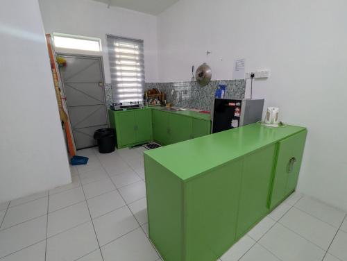 a kitchen with green cabinets and a refrigerator at HOMESTAY IBUNDA Sabak Bernam in Sabak Bernam