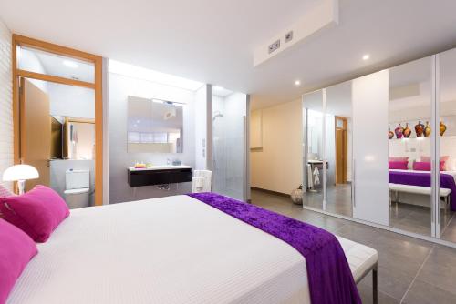 Un dormitorio con una gran cama blanca y un baño. en Suites Garden Loft El Greco, en Las Palmas de Gran Canaria