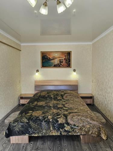 a bedroom with a large bed and a painting on the wall at Lux Apartment on Mayakovsky 6 in Ustʼ-Kamenogorsk