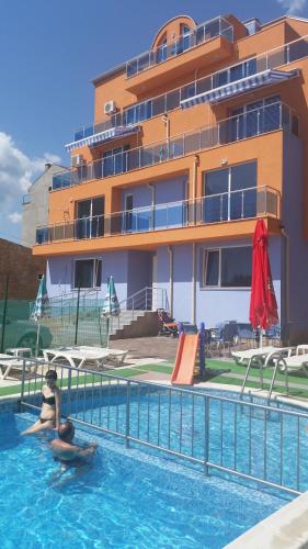 two people in a swimming pool in front of a building at Dara Hotel in Primorsko