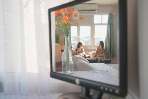 zwei Frauen sitzen im Wohnzimmer im Spiegel in der Unterkunft ที่พักใจ Teepakjai Nan in Nan
