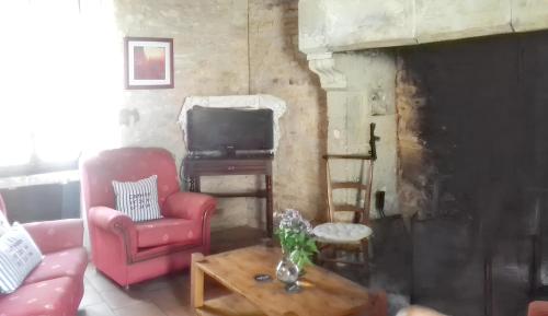 a living room with a red chair and a tv at Maison charmante à Lavercantière avec piscine partagée in Lavercantière
