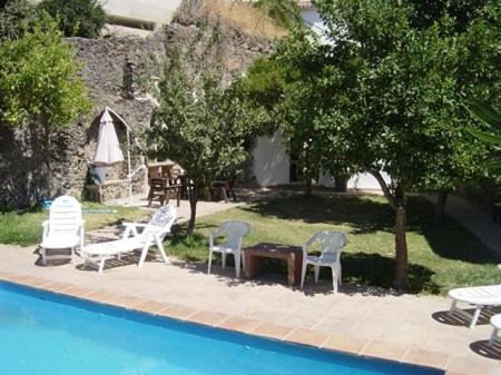 - un groupe de chaises et de tables à côté d'une piscine dans l'établissement Cortijo Retarta Jubrique, à Jubrique