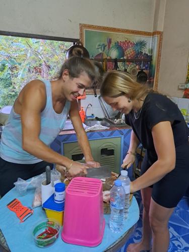 two people standing in a kitchen preparing food at Baan Klong House in Baan Khai