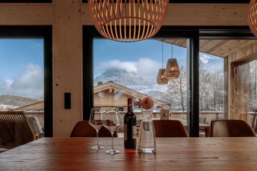 a table with two wine glasses and a mountain view at Alpenlodges in Schönau am Königssee