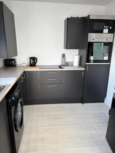 a kitchen with black cabinets and a washing machine at cozy two bedroom home in Hull