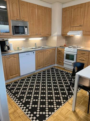 a kitchen with wooden cabinets and a black and white rug at Cozy 2BR Apartment KA64 with sauna in Oulu