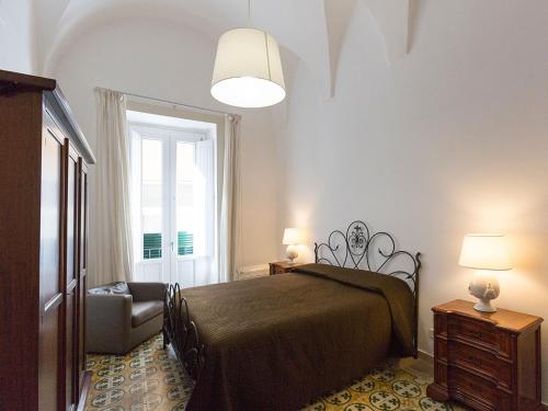 ein Schlafzimmer mit einem Bett, einem Stuhl und einem Fenster in der Unterkunft Nonna Jole in Lecce