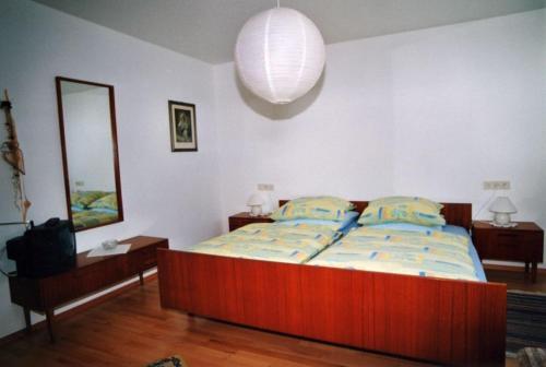 ein Schlafzimmer mit einem Bett, einem Spiegel und einer Lampe in der Unterkunft Haus Schindler in Ottenhöfen