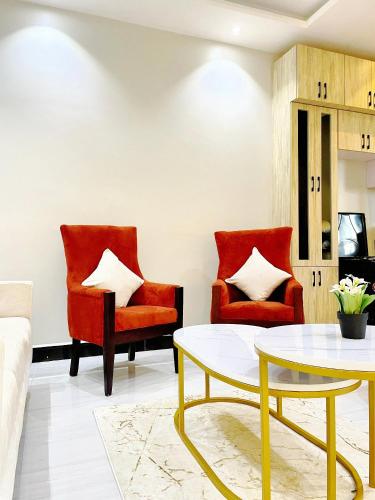 a living room with red chairs and a coffee table at SN suites apartment in Kampala