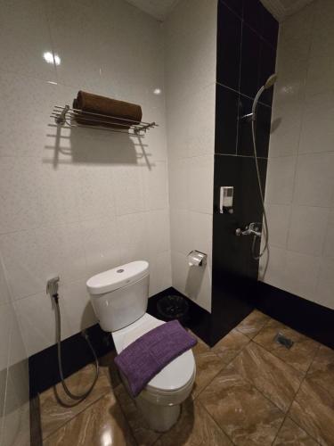 a bathroom with a toilet and a shower with a purple towel at Marilyn Hotel Serpong in Serpong
