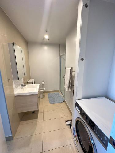 a bathroom with a sink and a washing machine at Spacious Magnificent Sea Views Front of Sky Tower in Auckland