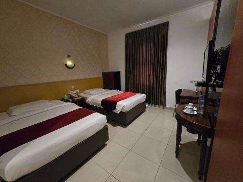a hotel room with two beds and a desk at Marilyn Hotel Serpong in Serpong