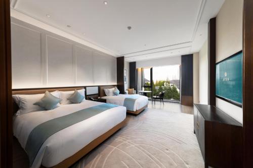 a hotel room with two beds and a television at Ningbo Xinzhi Hotel in Ningbo