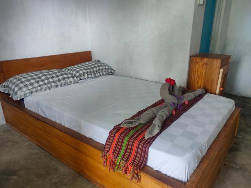 a bed with a wooden frame with a blanket on it at Twins Homestay ekas in Pulau Gilkaliantan