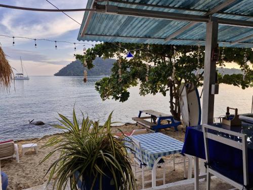 a beach with chairs and a table and the water at Secret Garden Family House in Ko Chang