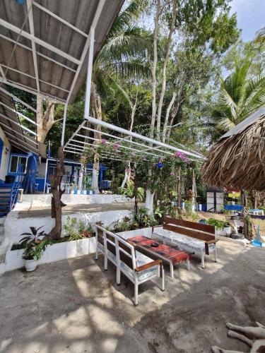 a patio with two benches and a building with trees at Secret Garden Family House in Ko Chang