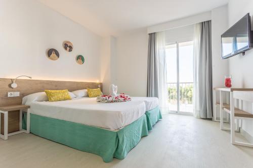 a bedroom with a large bed and a large window at Apartamentos Ferrer Tamarindos in Port d'Alcudia