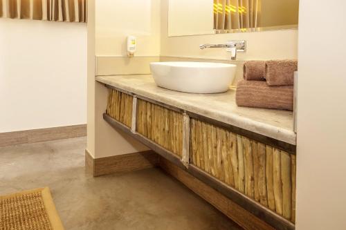 a bathroom with a white sink on a wooden counter at Desert Quiver Camp in Sesriem