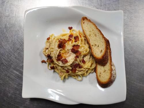 a white plate with pasta and a slice of bread at Villa Isabel Hotel in Sorsogon