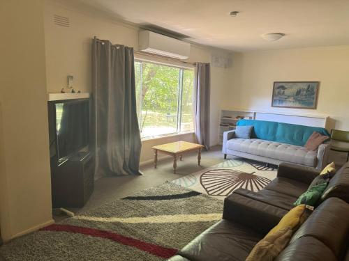 a living room with a couch and a tv at Ovensview On Riverside in Bright