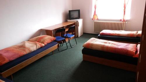 a room with two beds and a desk and a television at Hostel Karin in Ostrava