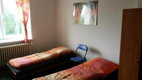 a bedroom with two beds and a blue chair at Hostel Karin in Ostrava