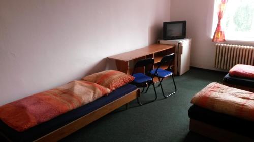 a room with a bed and a desk and chairs at Hostel Karin in Ostrava