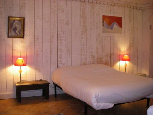 1 dormitorio con 1 cama blanca y 2 lámparas en La Maison Bleue, en La Cabanasse