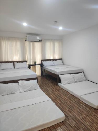 a room with four beds in it with windows at Manalo Resort Hotel in Tutulo