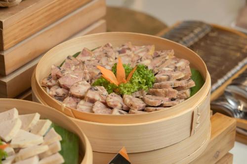 a bowl of food with meat and broccoli on a table at PANAMA Nha Trang Hotel in Nha Trang