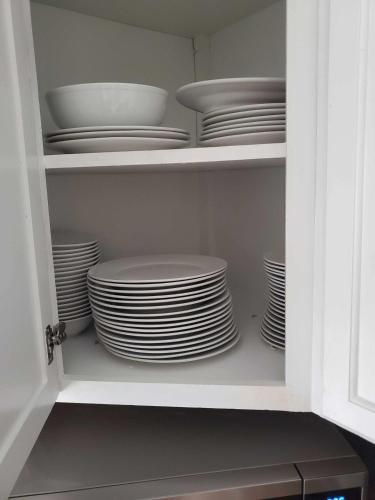 a cupboard filled with plates and dishes in at Two Kitchens Family Friendly in Forestdale in Birmingham